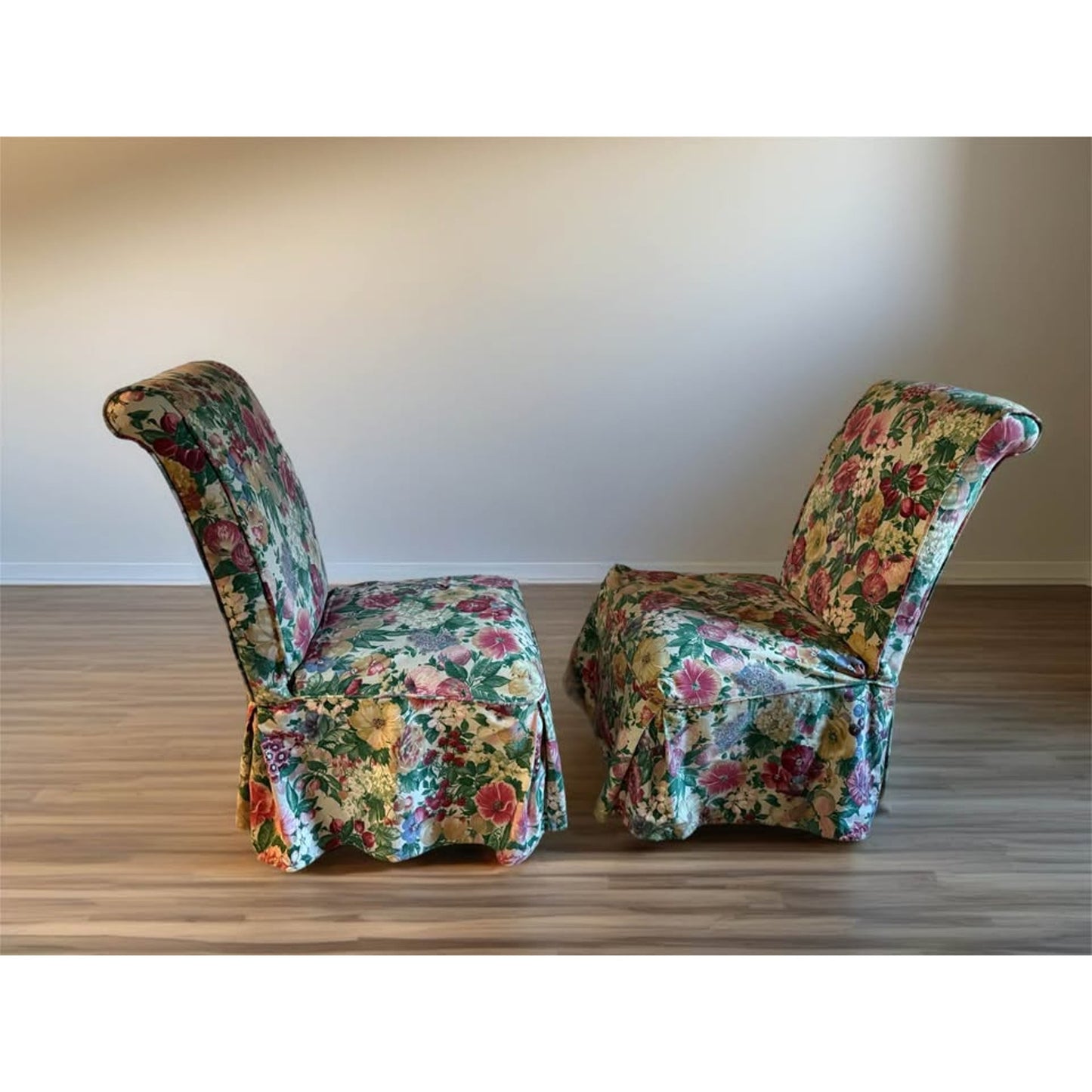 Pair of white upholstered chairs with floral covers over them