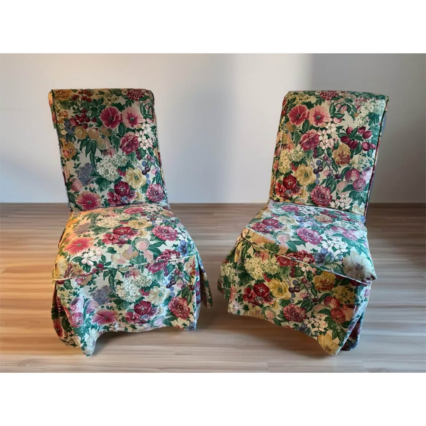 Pair of white upholstered chairs with floral covers over them