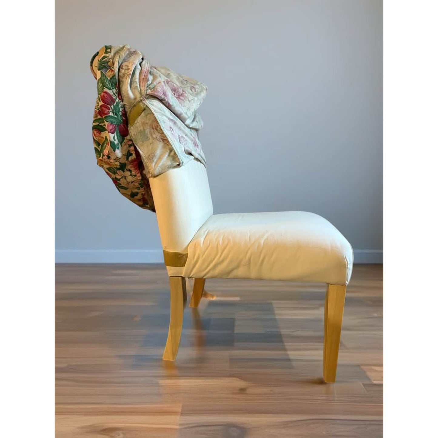 Pair of white upholstered chairs with floral covers over them