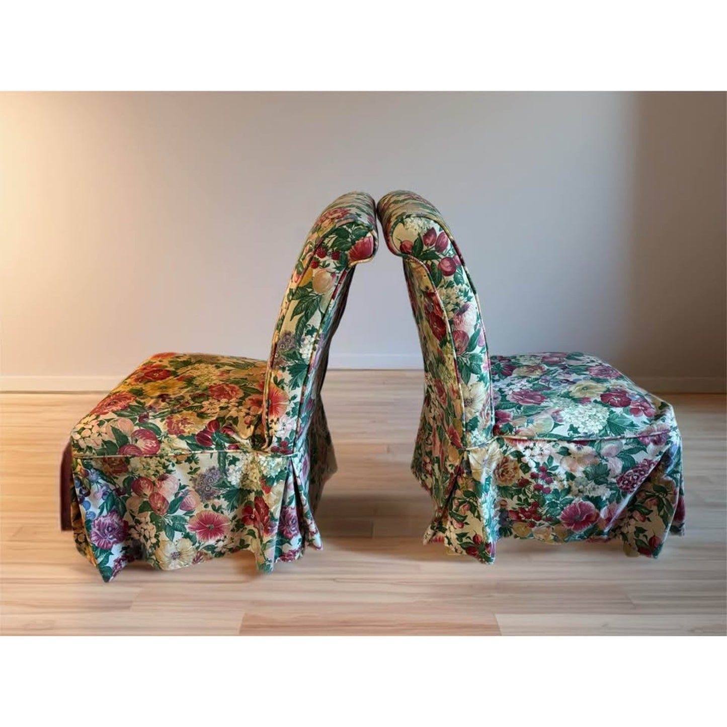 Pair of white upholstered chairs with floral covers over them